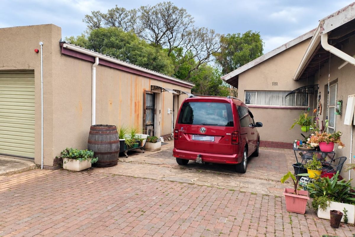 Rear exterior view of the property featuring a paved driveway, garage access, and visible rust staining on the exterior wall finish.