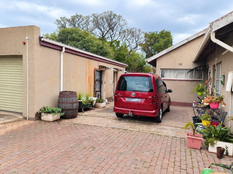 Rear exterior view of the property featuring a paved driveway, garage access, and visible rust staining on the exterior wall finish.