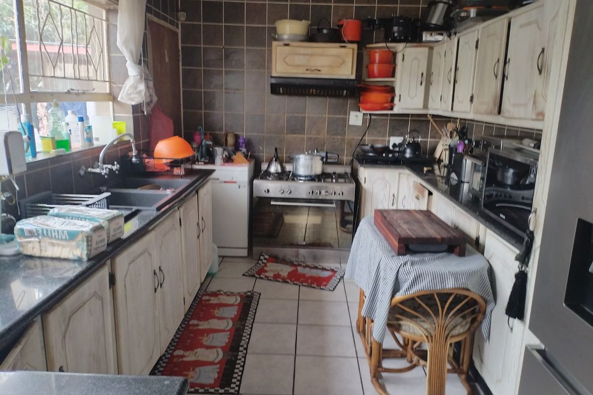 A functional kitchen featuring built-in cabinetry, a gas stove with extractor fan, and tiled finishes, offering potential for modernization and aesthetic updates.