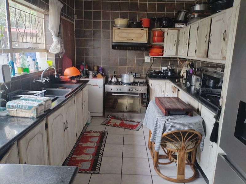 A functional kitchen featuring built-in cabinetry, a gas stove with extractor fan, and tiled finishes, offering potential for modernization and aesthetic updates.