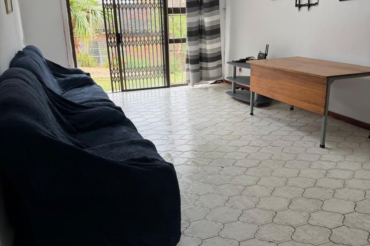 A living room featuring tiled flooring, a sliding glass door with a security gate, and direct access to the exterior.