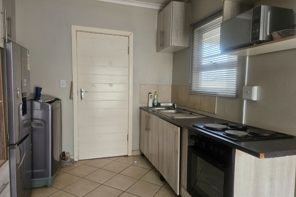 Compact kitchen featuring built-in cabinetry, laminate countertops, an electric hob, and an integrated oven with tiled flooring.