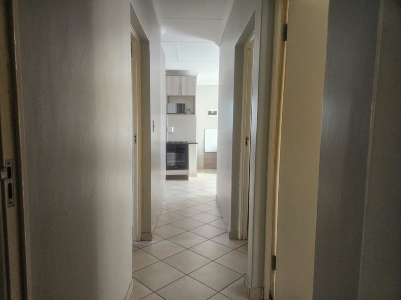 A view through a central hallway leading towards a kitchen area with tiled flooring and built-in cabinetry.