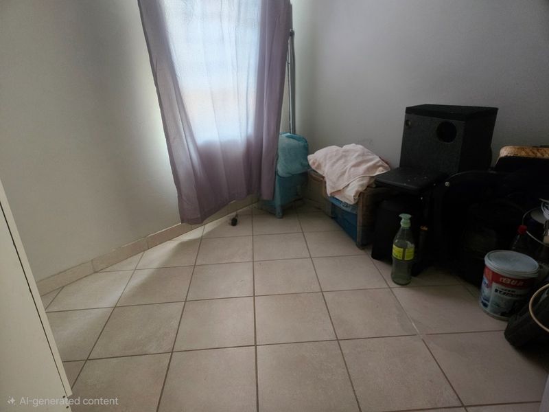 A small bedroom space featuring neutral tiled flooring and a window with curtains.