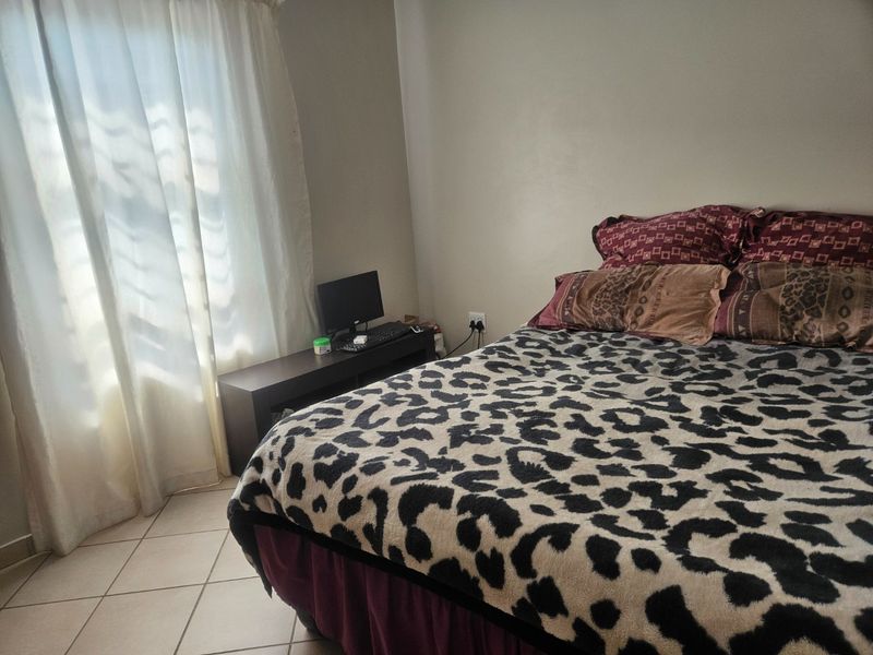 A bedroom featuring tiled flooring and natural light from a window with curtains.
