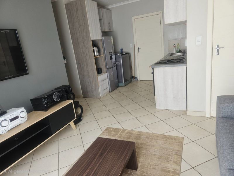 Open-plan living area featuring a compact kitchen with built-in cabinetry, gas hob, and tiled flooring throughout.