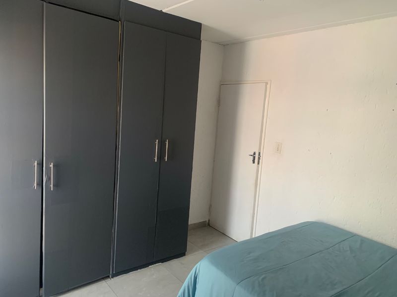 A bedroom featuring dark grey built-in cupboards and tiled flooring, providing functional storage space within the room.