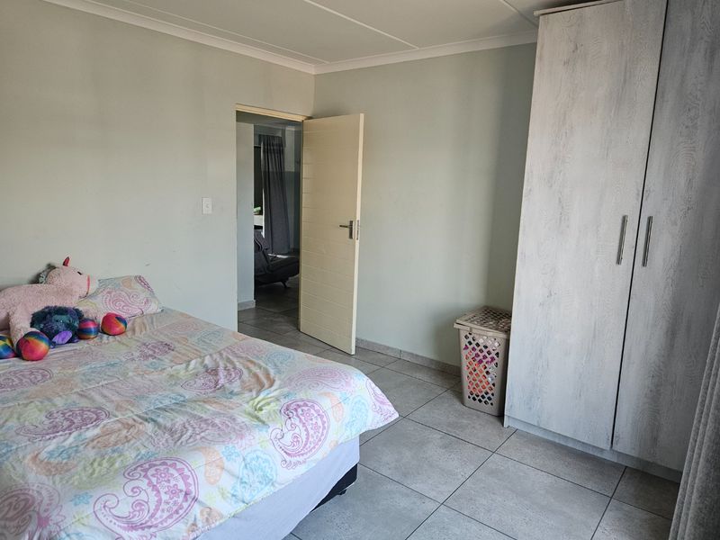 A bedroom featuring tiled flooring and a built-in wardrobe, providing functional storage space within the apartment.