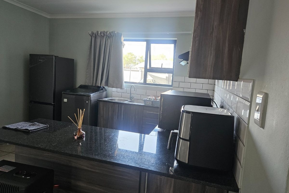A functional kitchen featuring dark wood cabinetry, granite countertops, and a classic white subway tile backsplash with a window for natural light.
