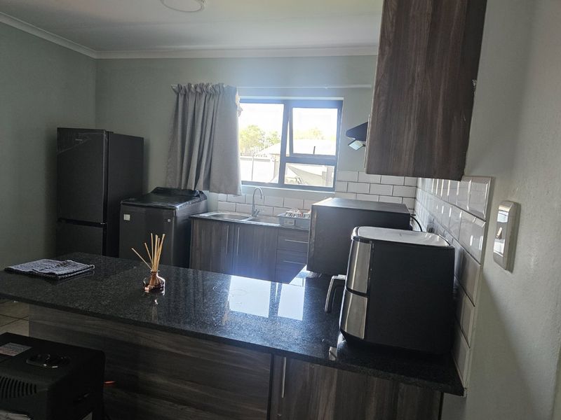 A functional kitchen featuring dark wood cabinetry, granite countertops, and a classic white subway tile backsplash with a window for natural light.