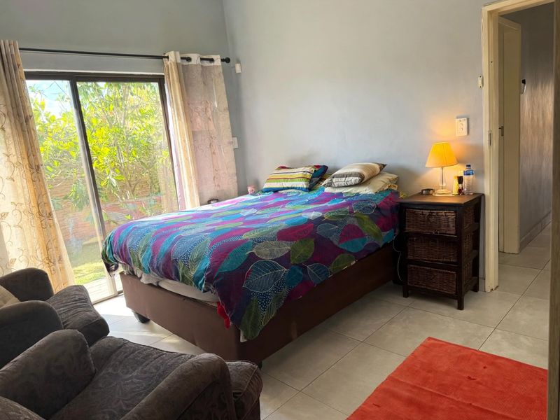 A bedroom featuring tiled flooring and a sliding glass door providing access to the exterior.