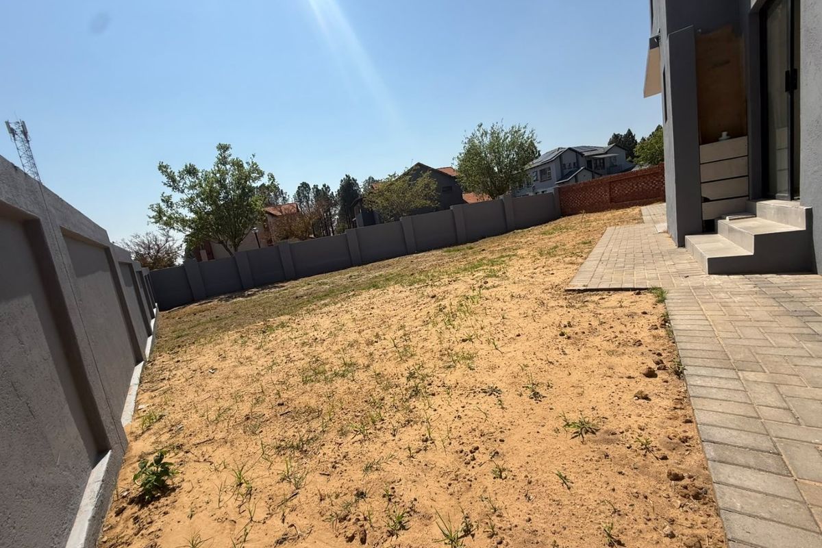 A rear garden area featuring a paved walkway, concrete steps, and a perimeter wall, currently awaiting landscaping and lawn installation.