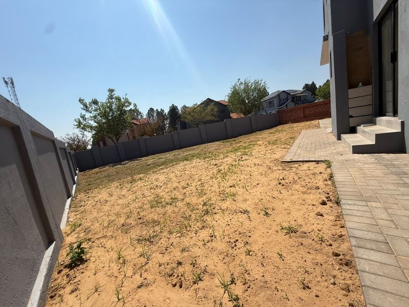 A rear garden area featuring a paved walkway, concrete steps, and a perimeter wall, currently awaiting landscaping and lawn installation.