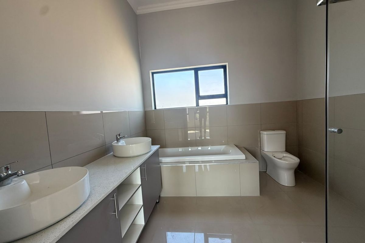 Modern bathroom featuring a double vanity with vessel sinks, a built-in bathtub, a separate glass shower enclosure, and neutral wall tiling.