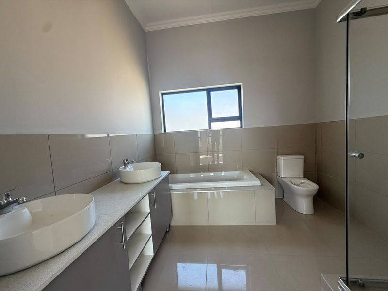 Modern bathroom featuring a double vanity with vessel sinks, a built-in bathtub, a separate glass shower enclosure, and neutral wall tiling.
