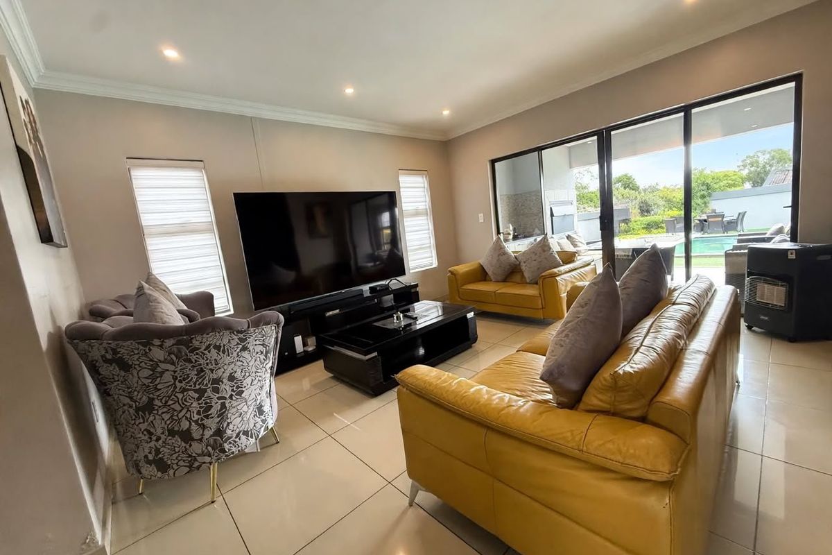 Spacious living room featuring large format floor tiles, recessed lighting, and expansive sliding glass doors providing seamless access to the outdoor pool area.