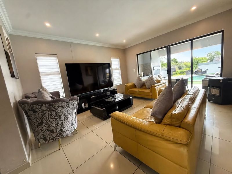 Spacious living room featuring large format floor tiles, recessed lighting, and expansive sliding glass doors providing seamless access to the outdoor pool area.
