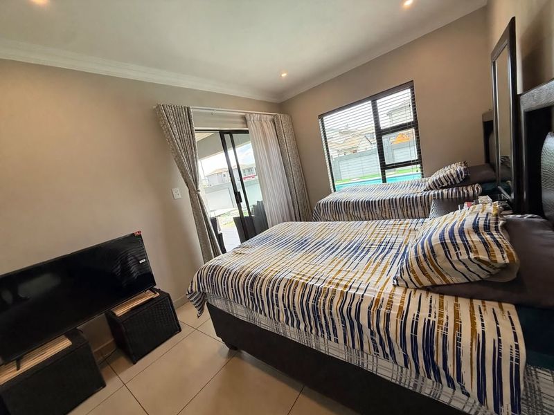 A well-maintained bedroom featuring tiled flooring, recessed downlighting, and a sliding glass door providing direct access to the outdoor area.