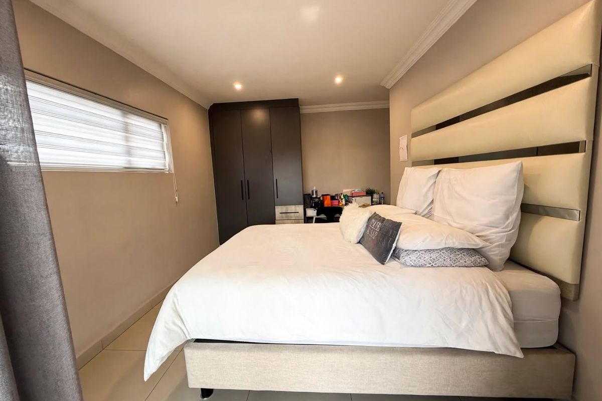 A well-maintained bedroom featuring tiled flooring, recessed downlighting, and a built-in wardrobe with modern finishes.