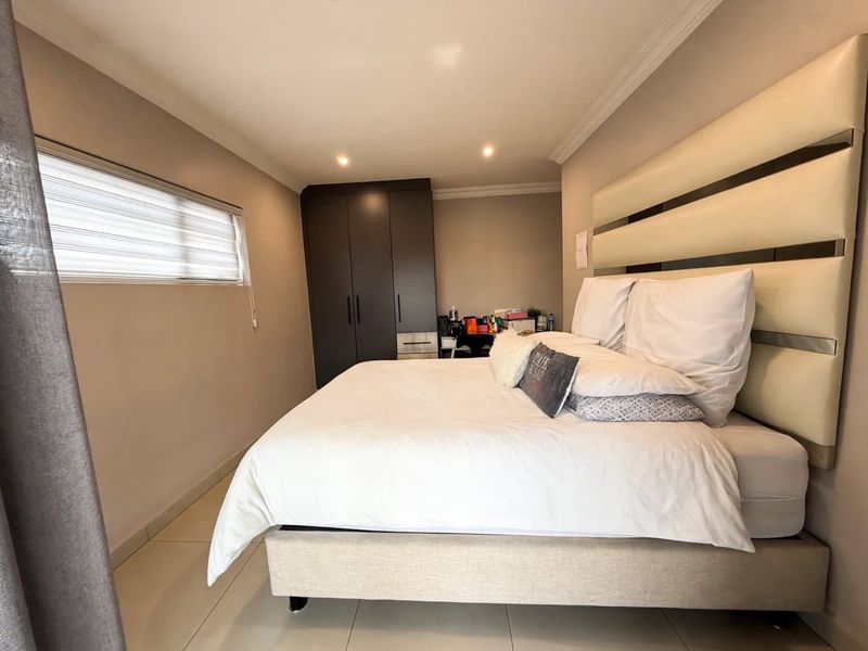 A well-maintained bedroom featuring tiled flooring, recessed downlighting, and a built-in wardrobe with modern finishes.