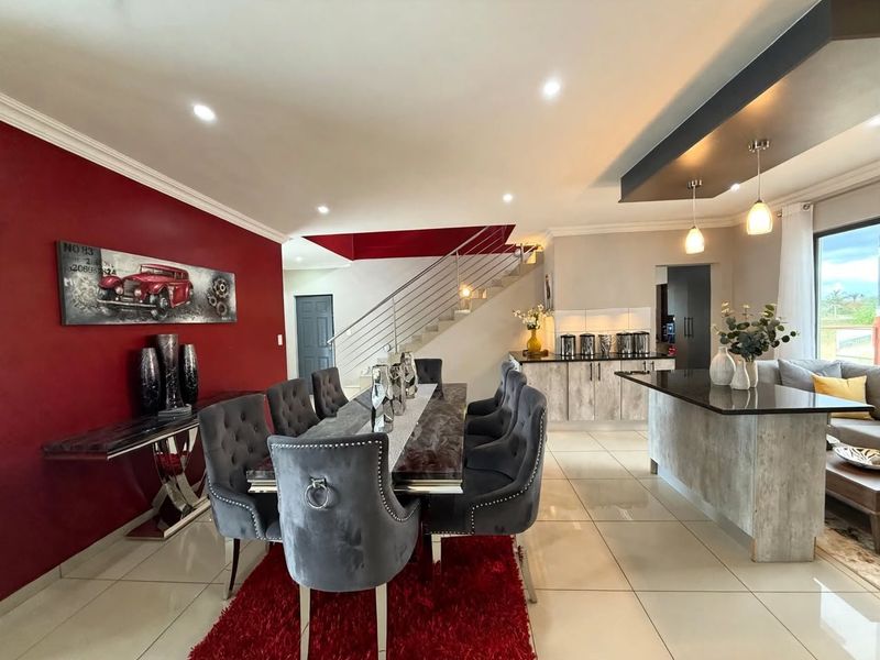 Spacious open-plan living and dining area featuring a modern kitchen island, sleek staircase, and contemporary finishes throughout.