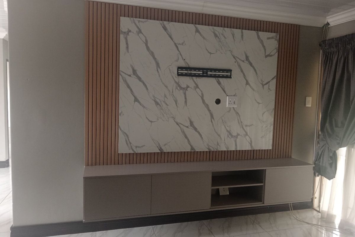 Modern living room featuring a custom built-in media console, marble-look feature wall with timber slat accents, and polished porcelain floor tiles.