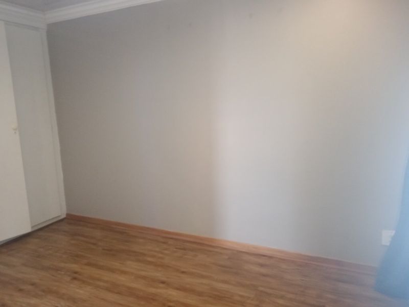 A clean, empty bedroom featuring laminate flooring, a built-in cupboard, and neutral wall finishes, providing a blank canvas for personalization.