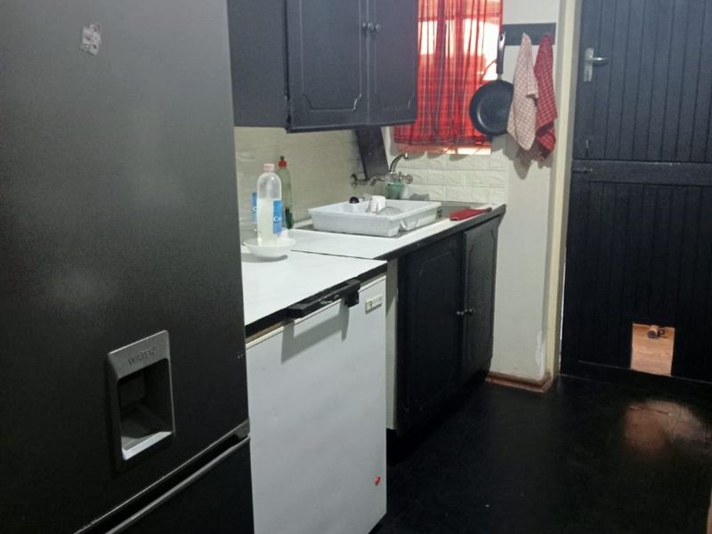 A compact scullery area featuring built-in cabinetry, a sink, and a stable door leading to the exterior.