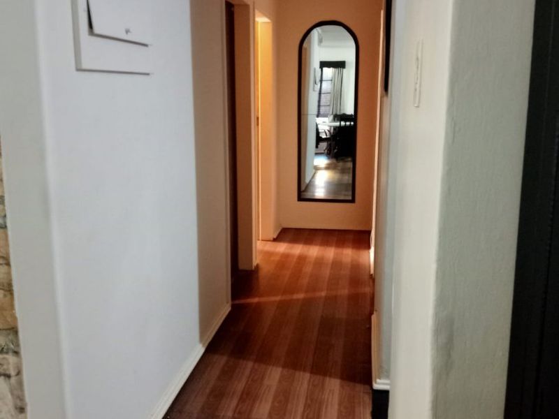 A functional hallway featuring laminate flooring and an arched wall mirror, providing access to adjacent rooms within the home.