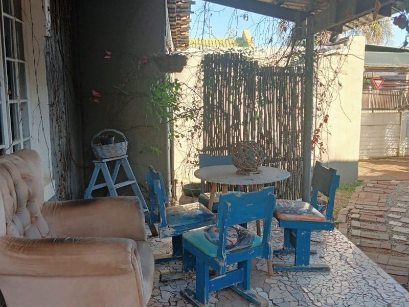 Covered outdoor patio area featuring a timber roof structure and mosaic-style crazy paving flooring, requiring maintenance and cosmetic updates.