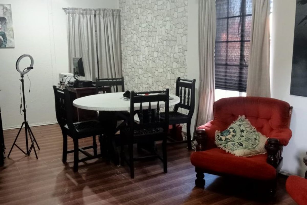 A living room featuring laminate flooring, a textured feature wall, and a window with a decorative pelmet.