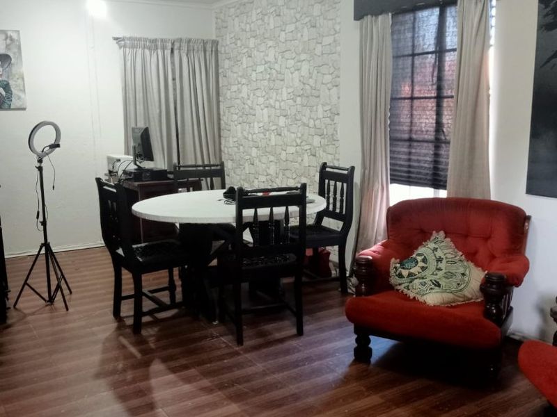 A living room featuring laminate flooring, a textured feature wall, and a window with a decorative pelmet.