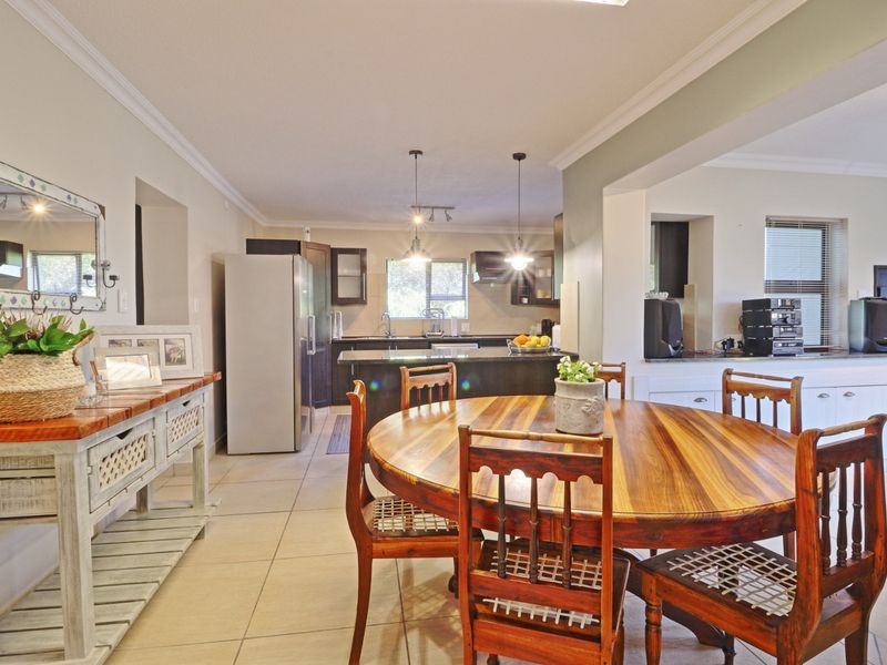 Open plan dining and kitchen area featuring tiled flooring, dark cabinetry with granite countertops, and modern pendant lighting.