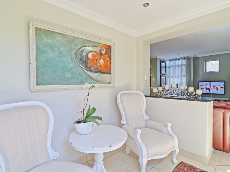 Open plan living area featuring tiled flooring, coved ceilings, recessed lighting, and a granite-topped breakfast bar connecting to the adjacent lounge space.