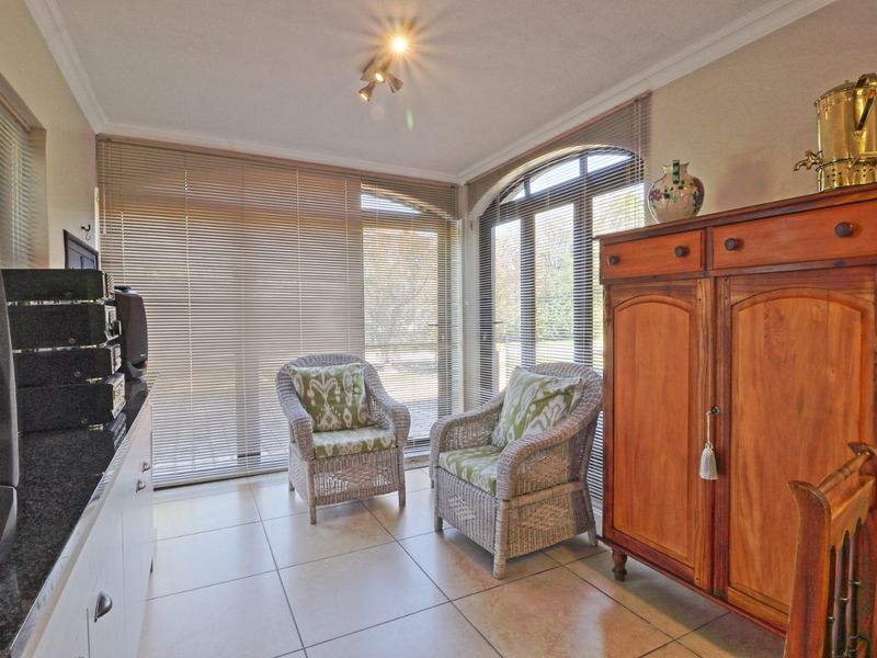 A sunlit living area featuring large arch-top windows with venetian blinds and neutral tiled flooring, offering a bright and comfortable space.