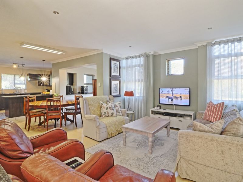 Spacious open-plan living and dining area featuring tiled floors, recessed lighting, and a modern kitchen with built-in cabinetry and appliances.