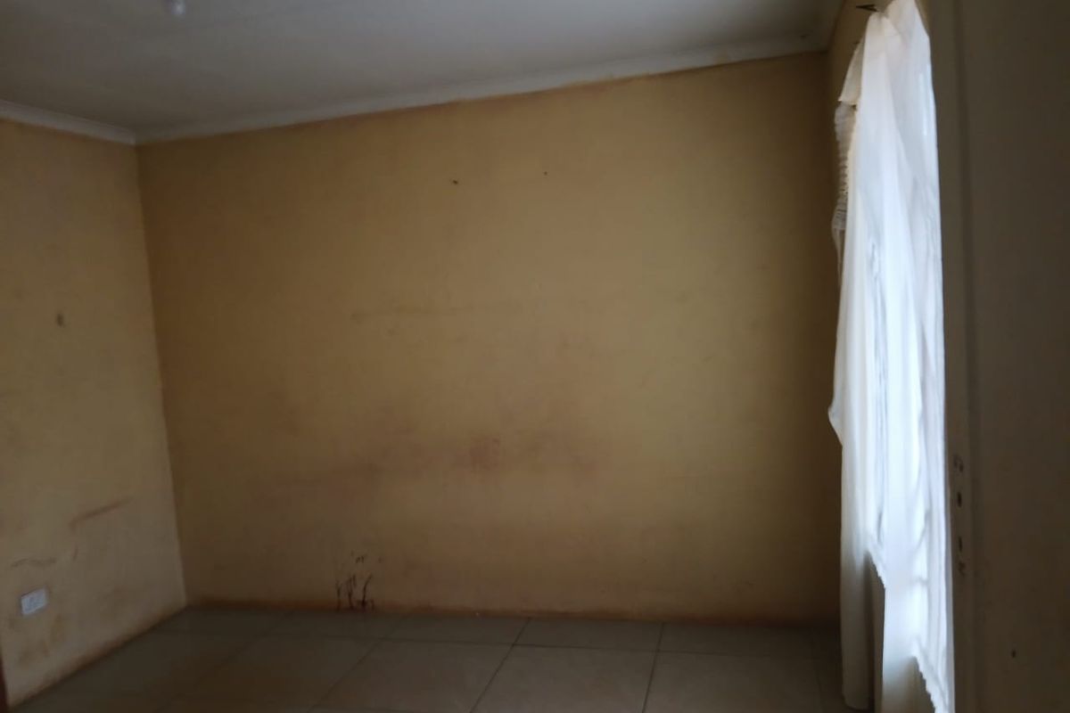 An empty bedroom featuring tiled flooring and coved ceilings, currently requiring cosmetic updates to the wall finishes.