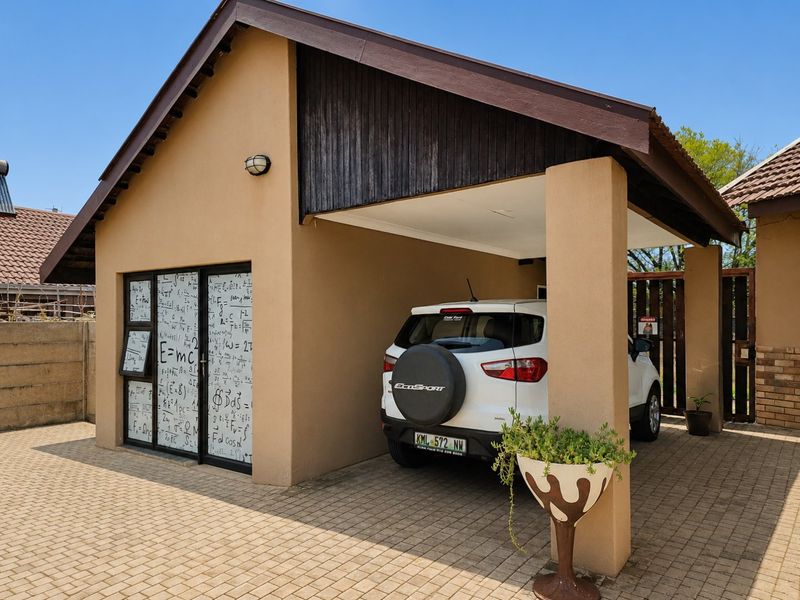 Front exterior view of a commercial property featuring a covered carport, paved driveway, and a modern sliding glass entrance with decorative window film.