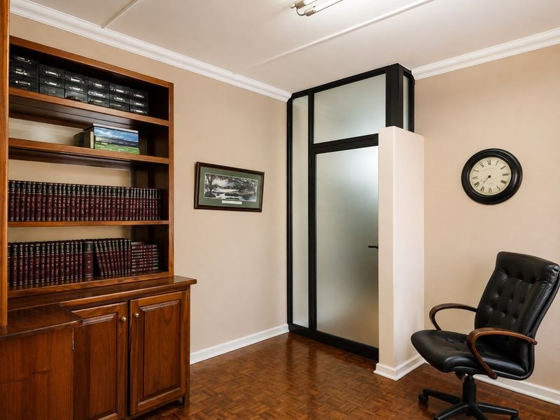 A professional office space featuring built-in wooden cabinetry, parquet flooring, and a modern frosted glass partition wall.