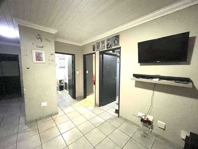 A living area featuring tiled flooring and a timber ceiling, providing access to adjacent rooms through internal doorways.
