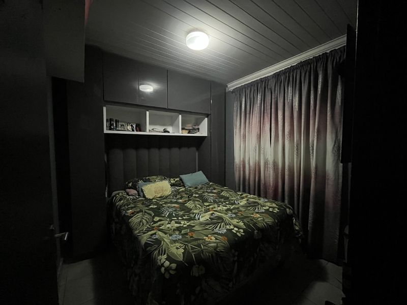 A bedroom featuring built-in cupboards with overhead storage, a tongue and groove ceiling, and coving detail.