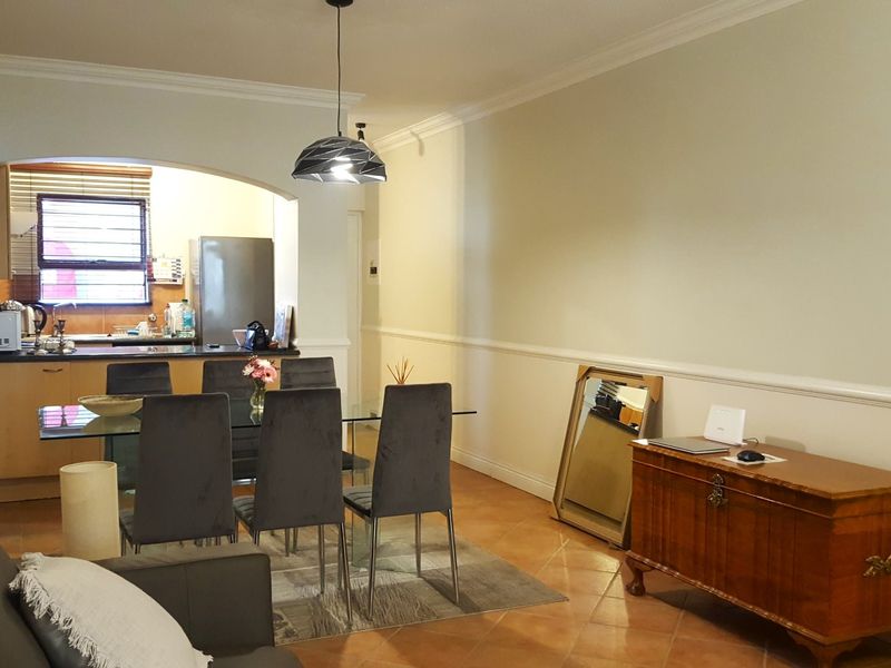 Open plan living and dining area featuring tiled floors, chair rail molding, and an arched transition into the kitchen space.