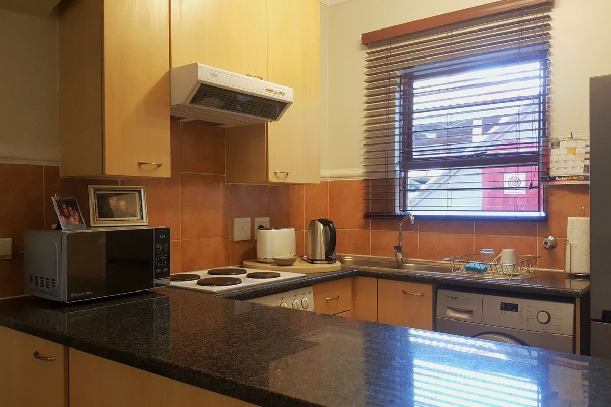 Functional kitchen featuring granite countertops, tiled backsplash, built-in cabinetry, and integrated appliances, offering a practical layout for daily use.