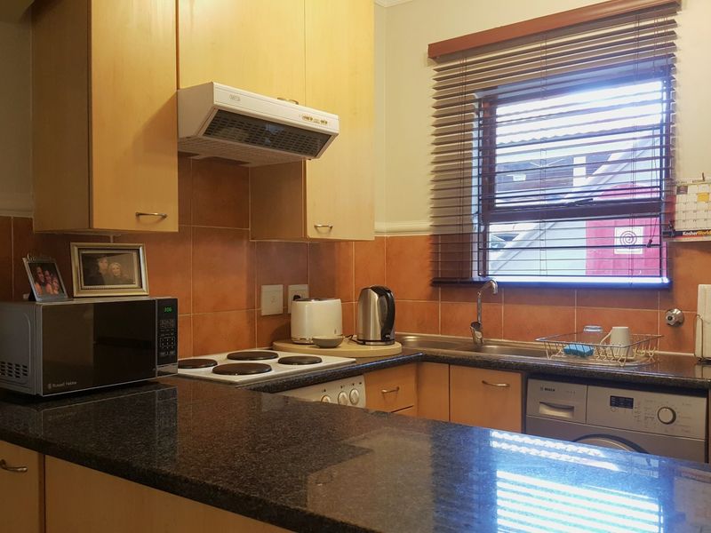 Functional kitchen featuring granite countertops, tiled backsplash, built-in cabinetry, and integrated appliances, offering a practical layout for daily use.