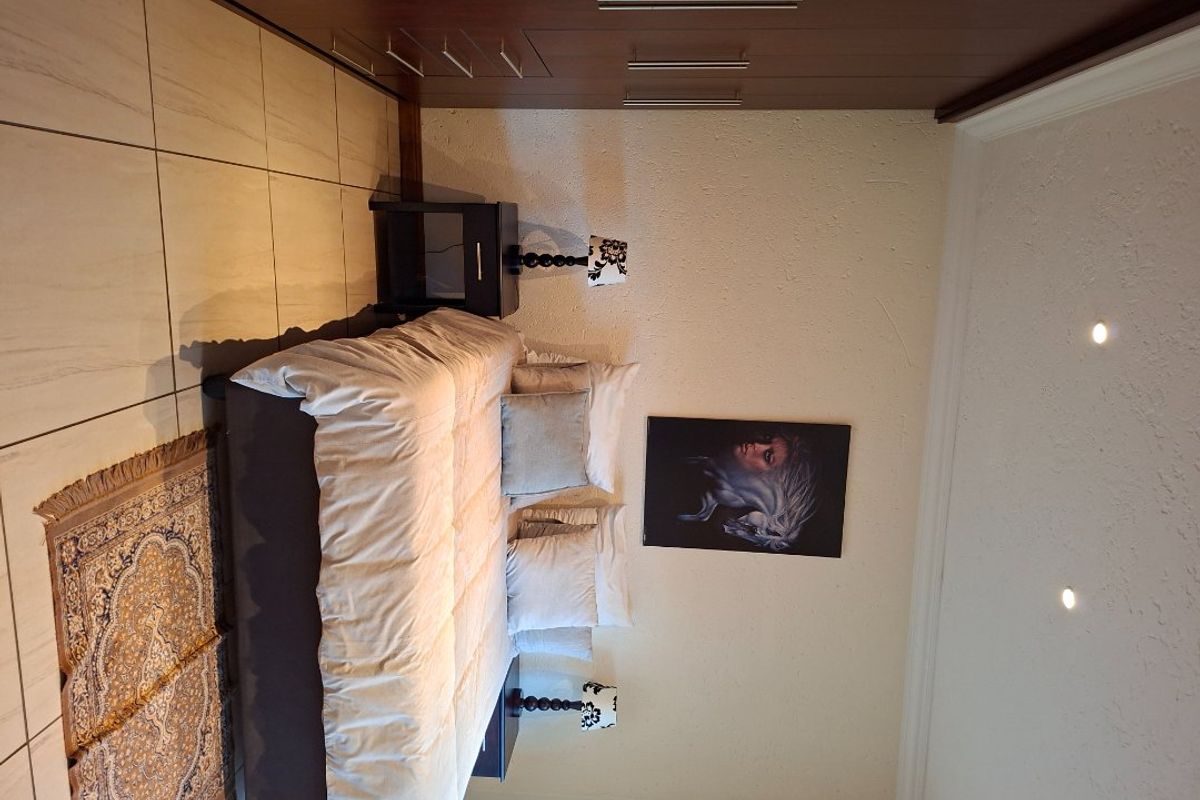 A well-maintained bedroom featuring built-in cupboards, recessed downlighting, and tiled flooring, offering a clean and functional living space.