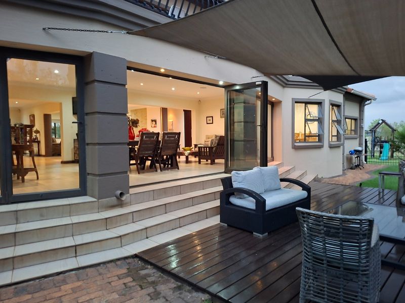 Spacious outdoor patio featuring timber decking, tiled steps, and large fold-away glass doors providing seamless indoor-outdoor flow.