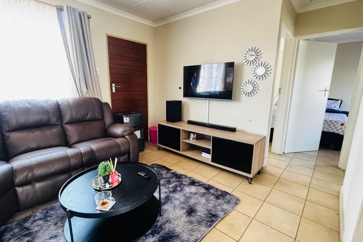 A comfortable living room featuring tiled flooring and neutral wall tones, providing a functional and well-lit space for relaxation.
