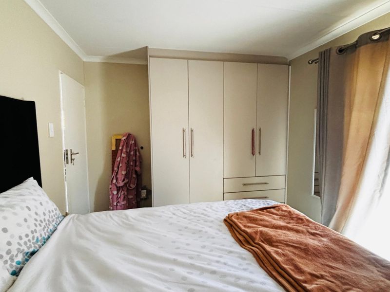 A functional bedroom featuring built-in cupboards with integrated drawers and neutral wall finishes, providing practical storage and a comfortable living space.