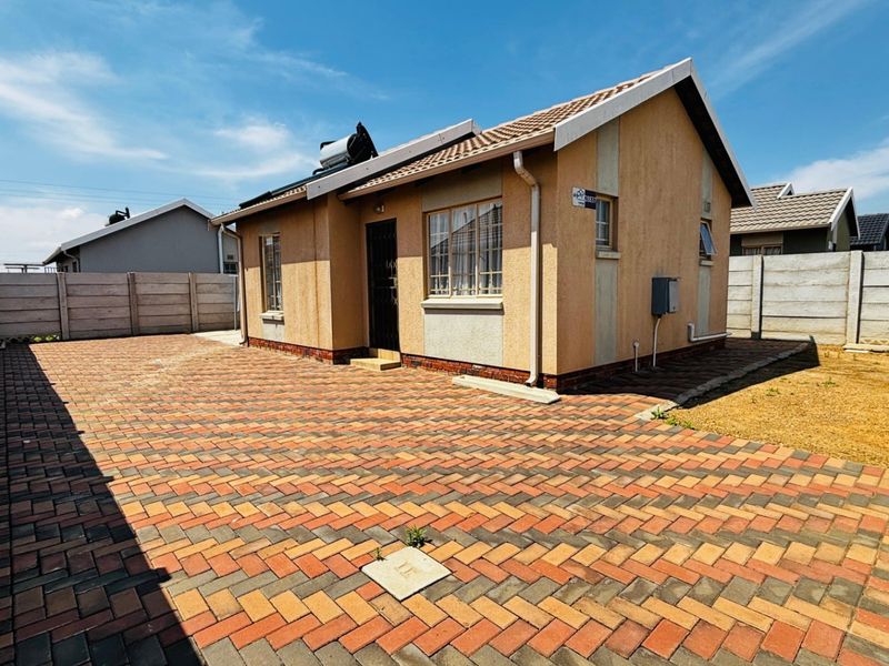 A well-maintained single-story house featuring a paved driveway, solar geyser, and secure precast boundary walls.