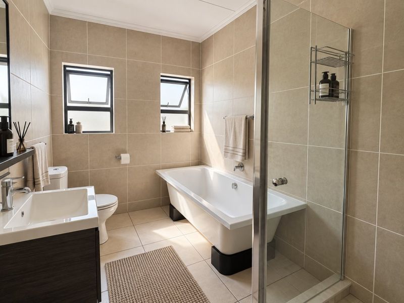 A well-maintained bathroom featuring a freestanding bathtub, a separate glass-enclosed shower, a modern vanity, and neutral floor-to-ceiling tiling.